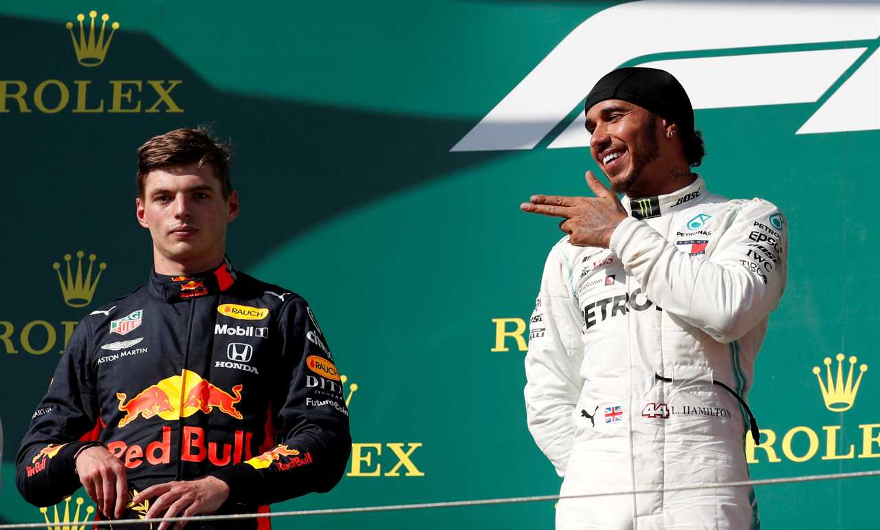 A Formula 1 driver points his fingers at an unimpressed rival on the podium after a Grand Prix race.