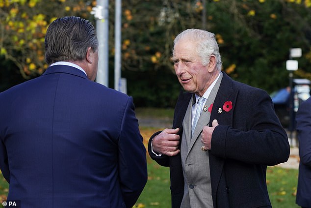 Prinz Charles trug heute einen marineblauen Mantel - mit Mohnblume sowohl auf seiner Anzugjacke als auch auf seinem wärmeren Mantel.  Er wurde von Zak Brown, Chief Executive von McLaren Racing, links begrüßt