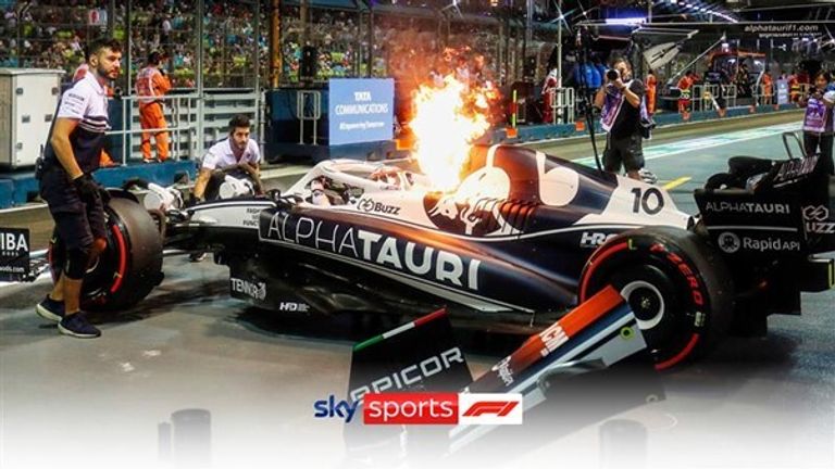 Pierre Gasly jumps out of his car as flames shoot out of the air vent after he pulled into the pits at the Singapore Grand Prix.