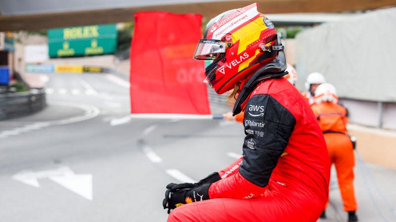 A photo of Ferrari driver Carlos Sainz sitting on a fence in Monaco. 