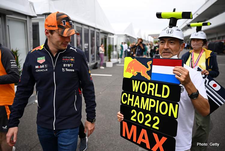 SUZUKA, JAPAN - OCTOBER 06: Max Verstappen of the Netherlands and Oracle Red Bull Racing walks in the Paddock next a fan holding a pit board showing their support during previews ahead of the F1 Grand Prix of Japan at Suzuka International Racing Course on October 06, 2022 in Suzuka, Japan.  (Photo by Clive Mason/Getty Images)